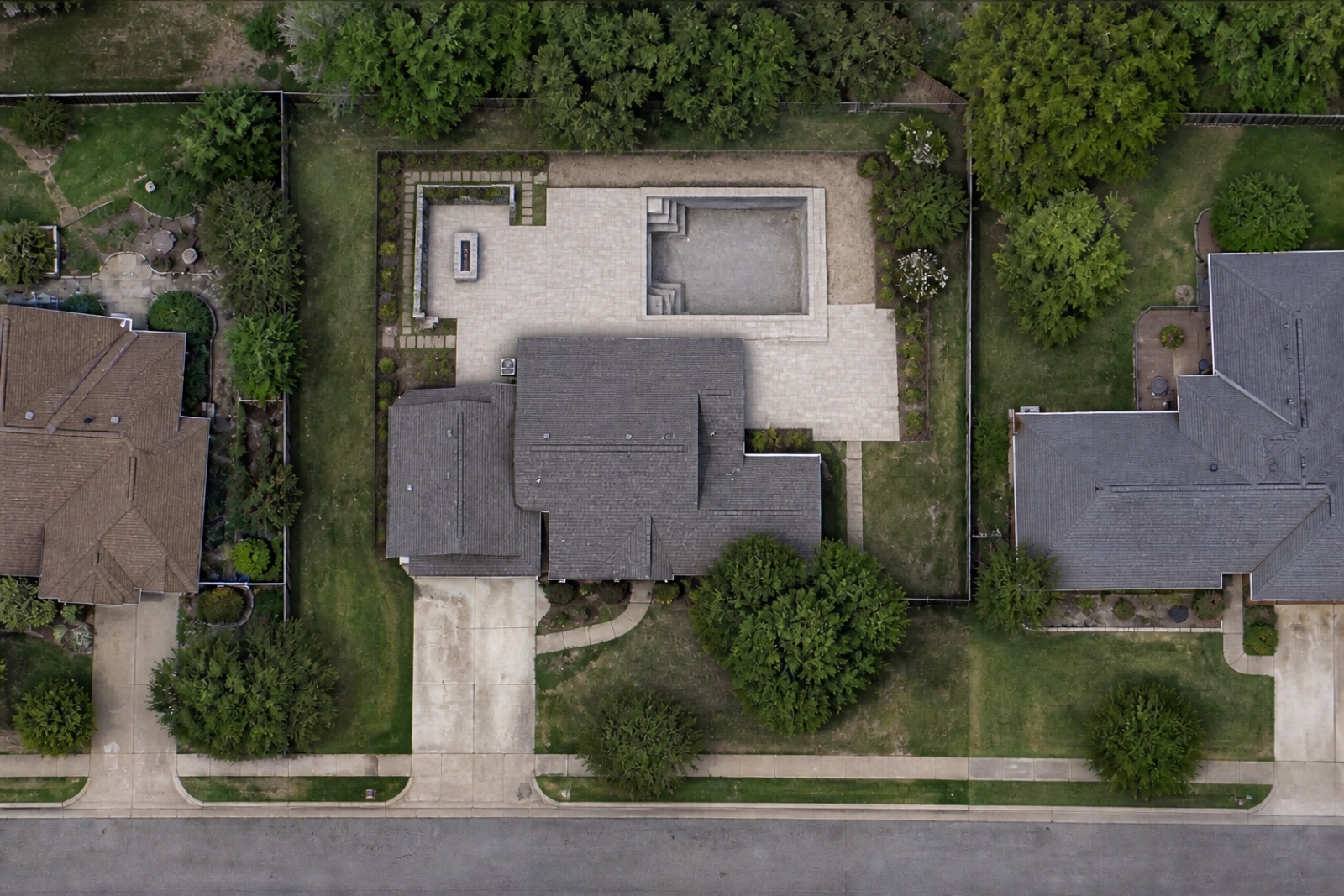 Illustrative current aerial view of the same suburban home with new paving and a partially completed pool behind the house